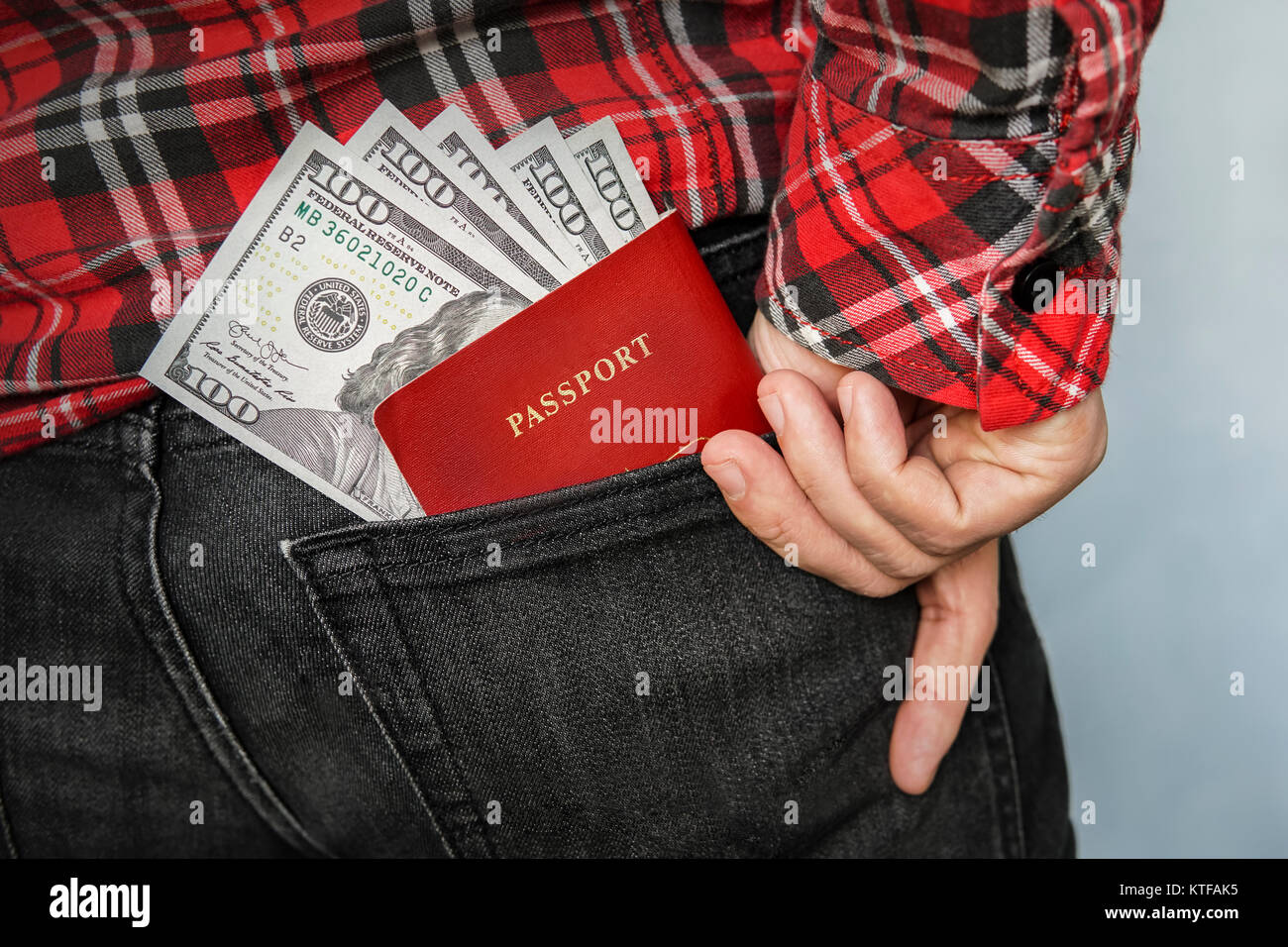 Man gets money and a passport from the back pocket of black jeans. Out