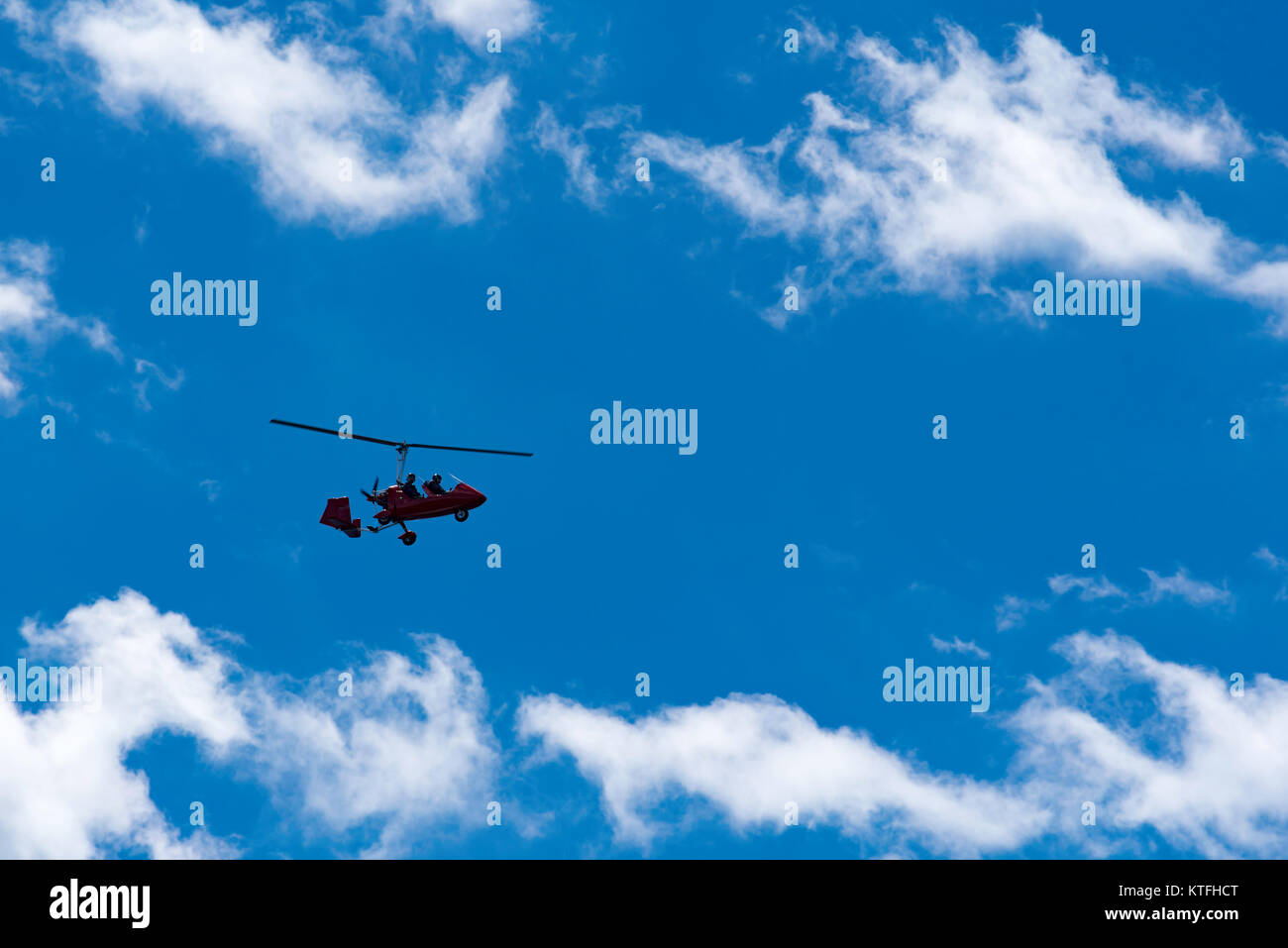 A microlight gyro-copter silhouetted against a blue sky, flying in Sydney, Australia Stock Photo