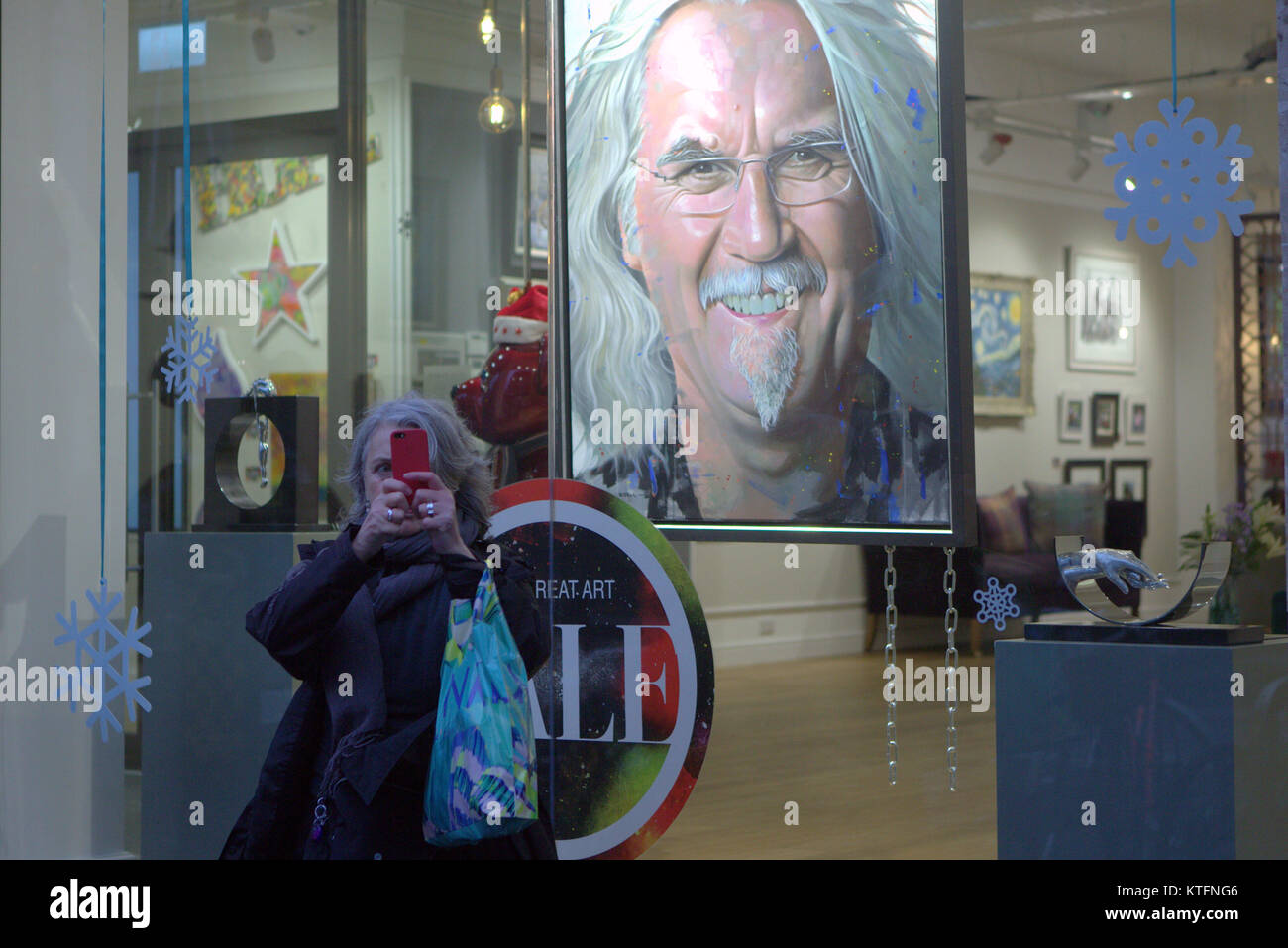 Christmas Eve and a fan snaps a selfie with billy Connolly  art print  in Castle Fine Art queen street near the city’s George square. Credit Gerard Ferry/Alamy news Stock Photo