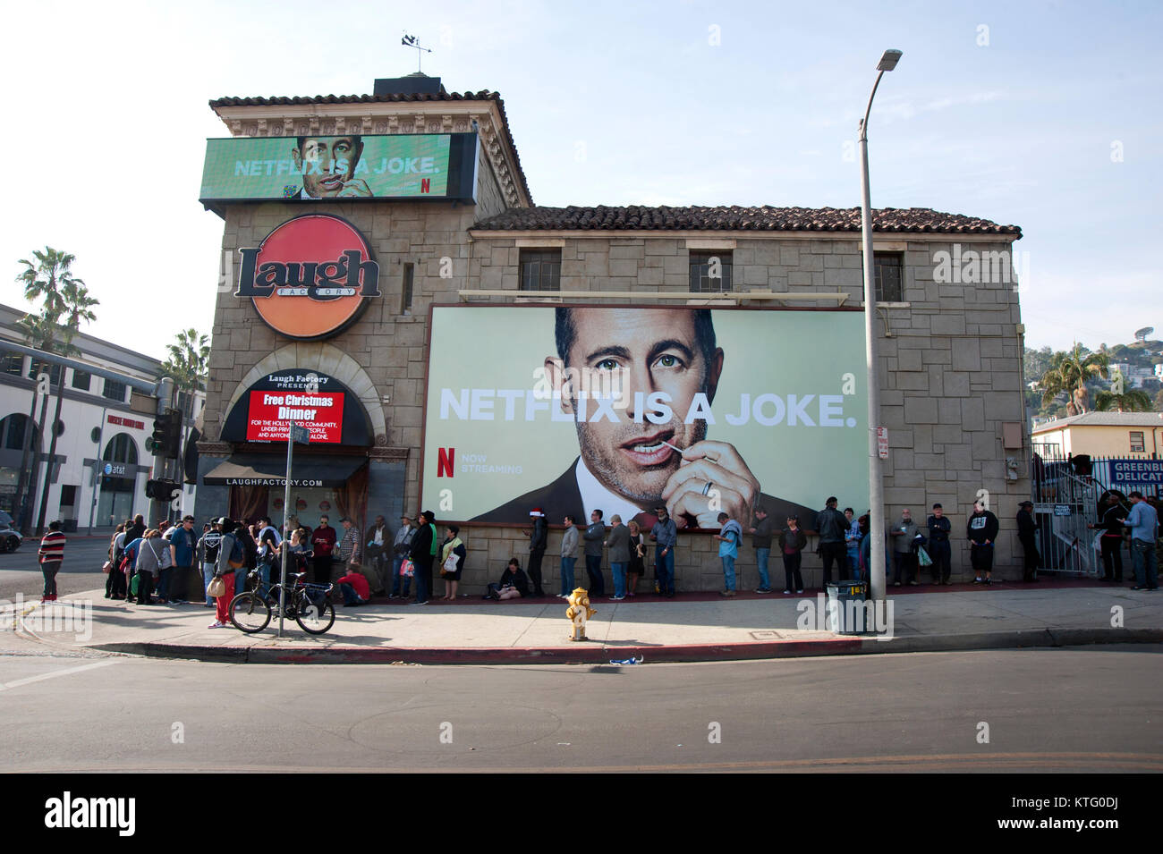 Los Angeles, USA. 25th Dec, 2017. People line up on Christmas day for a free meal beneath a billboard of Jerry Seinfeld with a tooth pick at the Laugh Factory on the Sunset Strip in Los Angeles. Credit: Robert Landau/Alamy Live News Stock Photo