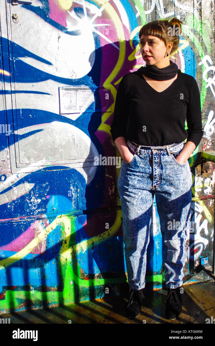 Sion, Switzerland, 23rd Dec 2017. Woman in 8os vintage jeans pressed up  against wall of graffiti Stock Photo - Alamy