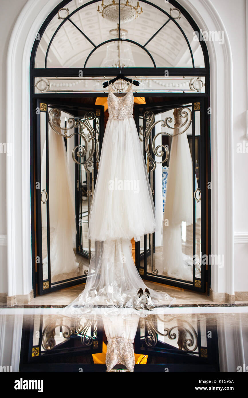 Wedding dress hanging on the door in the white room Stock Photo - Alamy