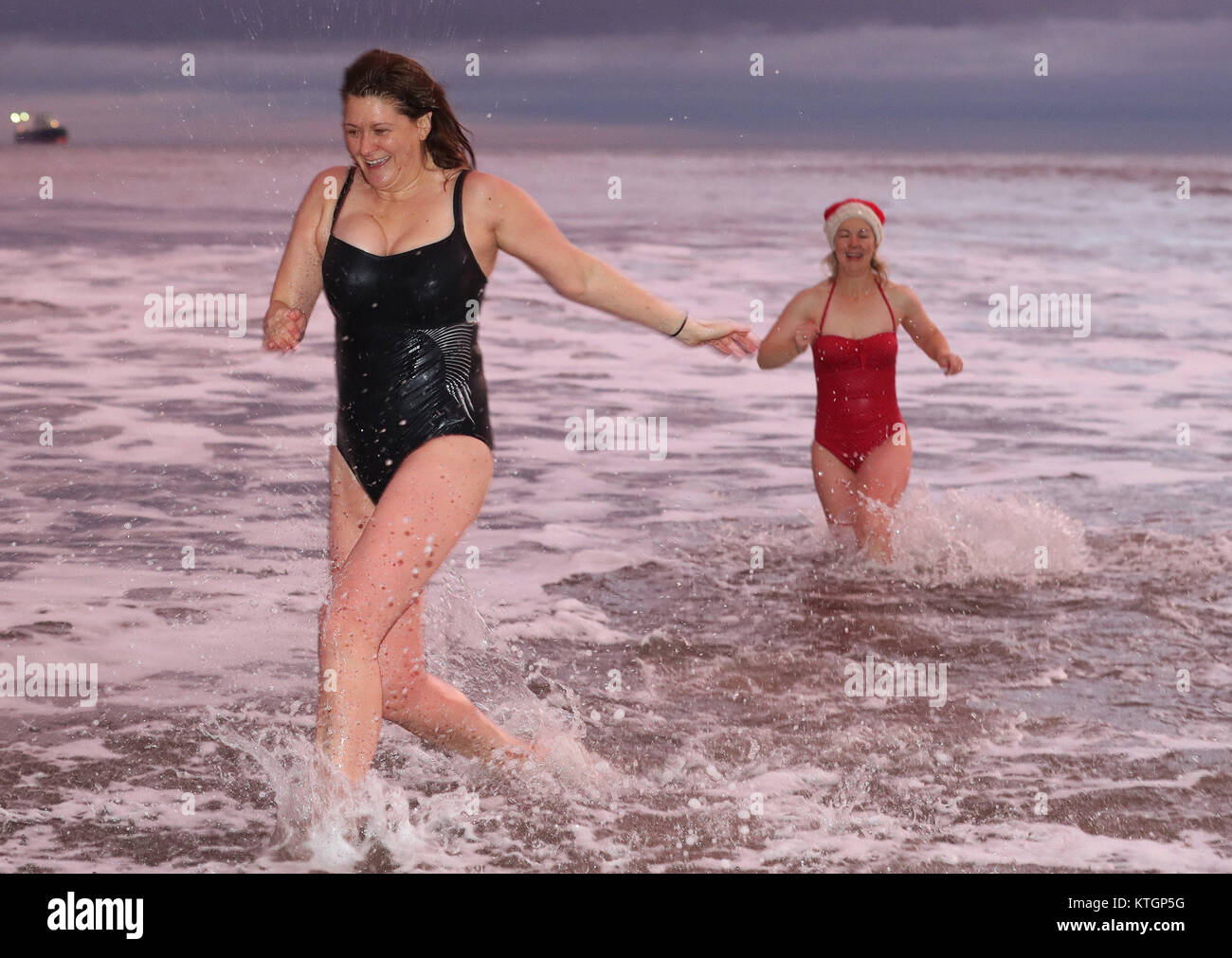 Kerri Elston Doherty (right) and Estelle Zauner Maughan of The King Edward's Bay swimmers enjoy a Christmas Day Dip at sunrise, at King Edward's Bay, Newcastle. Stock Photo
