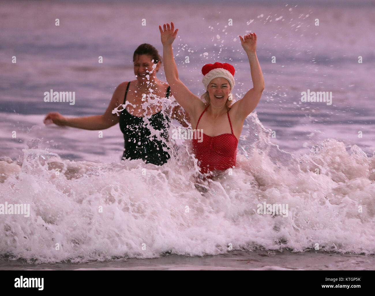Kerri Elston Doherty (centre) and Estelle Zauner Maughan (centre left) of The King Edward's Bay swimmers enjoy a Christmas Day Dip at sunrise, at King Edward's Bay, Newcastle. Stock Photo