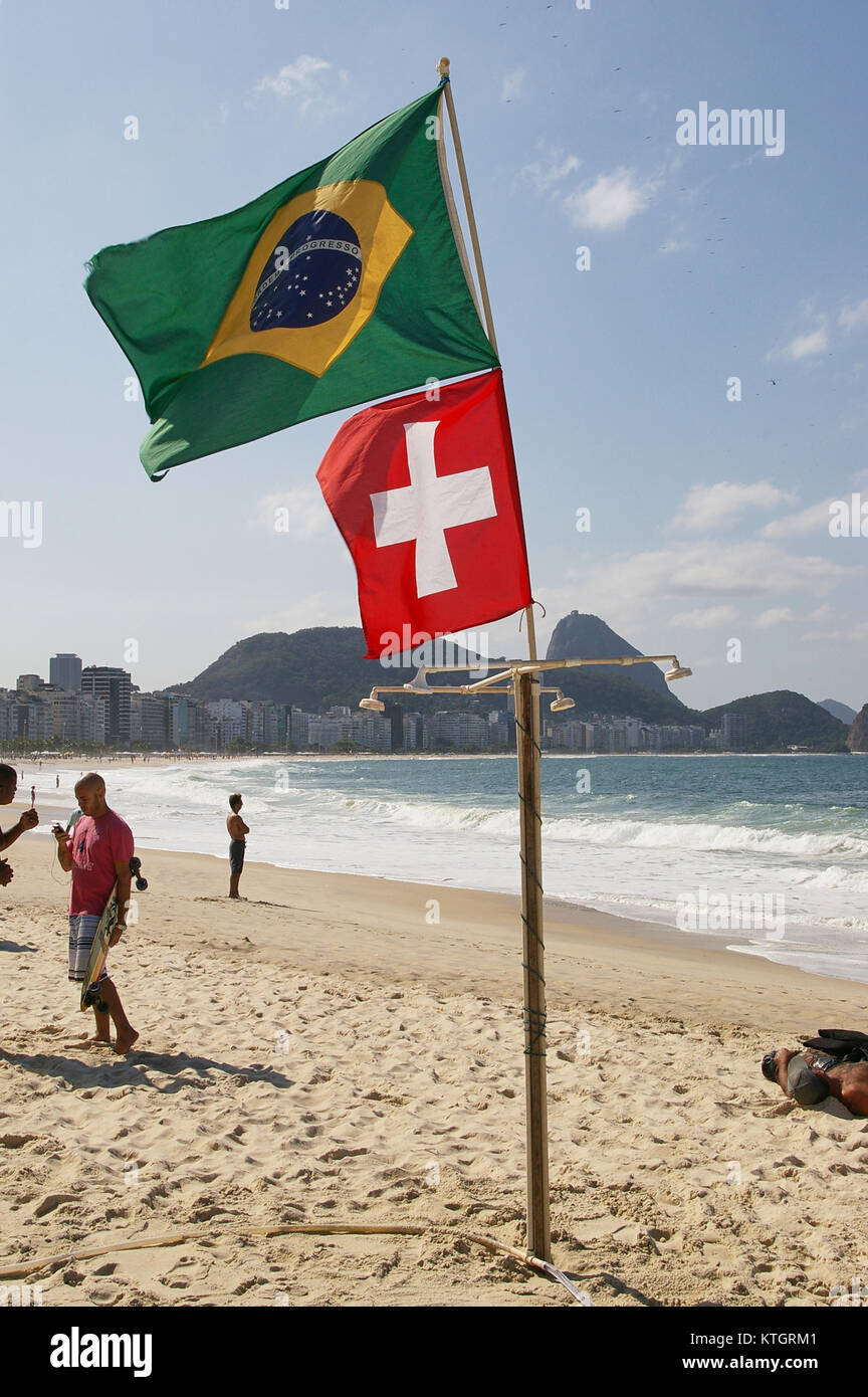 Brazilian and Swiss flags on the Copacabana beach in Rio de Janeiro, Brazil, with sugar loaf (corcovado) in the background. Stock Photo