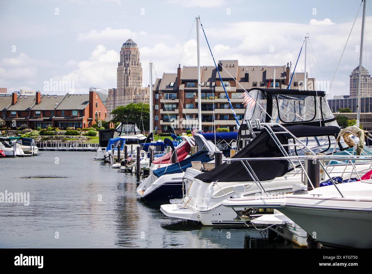 Exterior boats resting in Erie Basin Marina in foreground and apartments and Buffalo City Hall in background in Buffalo New York in Erie County Stock Photo