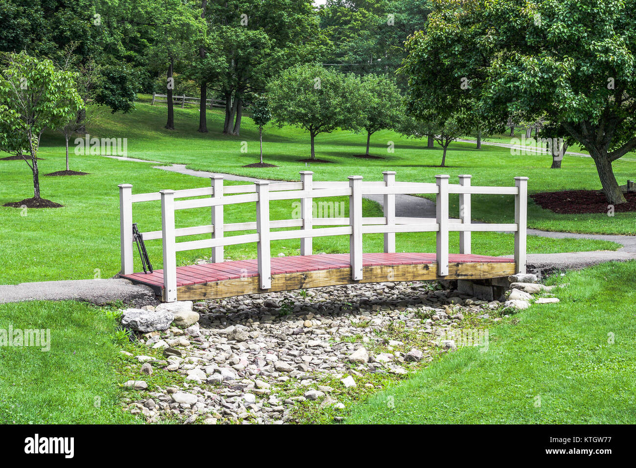 Exterior daytime red and white wooden bridge spanning dry creek bed