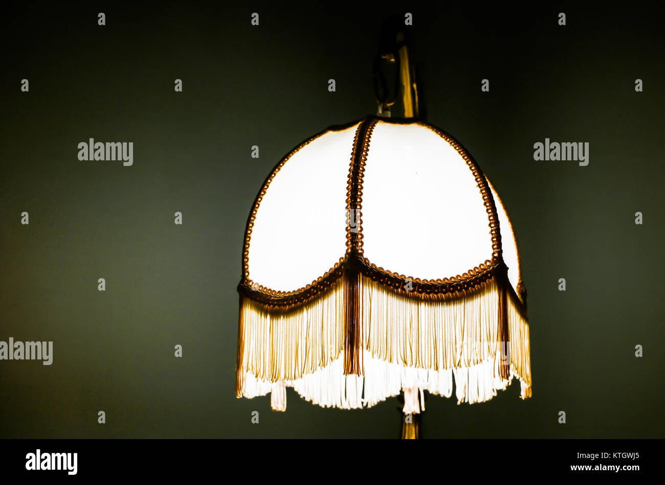 Interior high contrast stock photo of bright antique lamp isolated against olive background Stock Photo