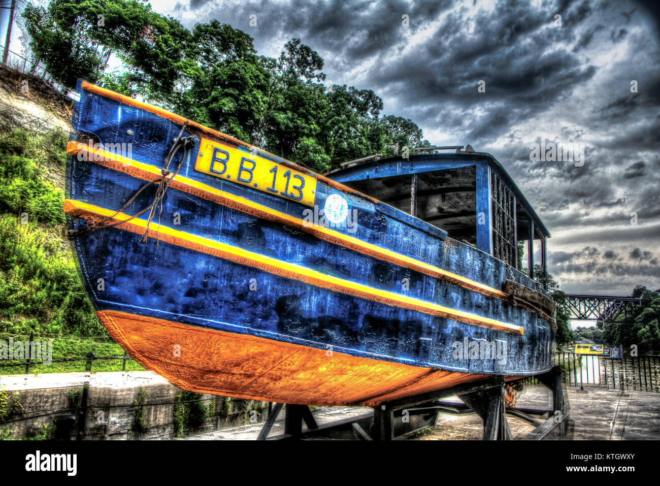 High dynamic range stock photo of blue wooden boat with yellow bottom on cloudy day at lockport lock in Lockport, New York in Niagara County Stock Photo