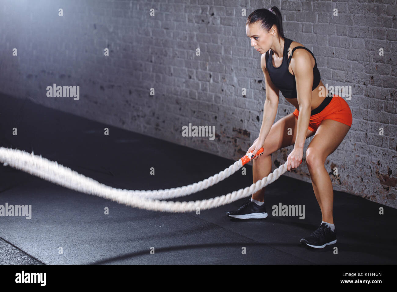 Woman training with battle rope in cross fit gym Stock Photo - Alamy