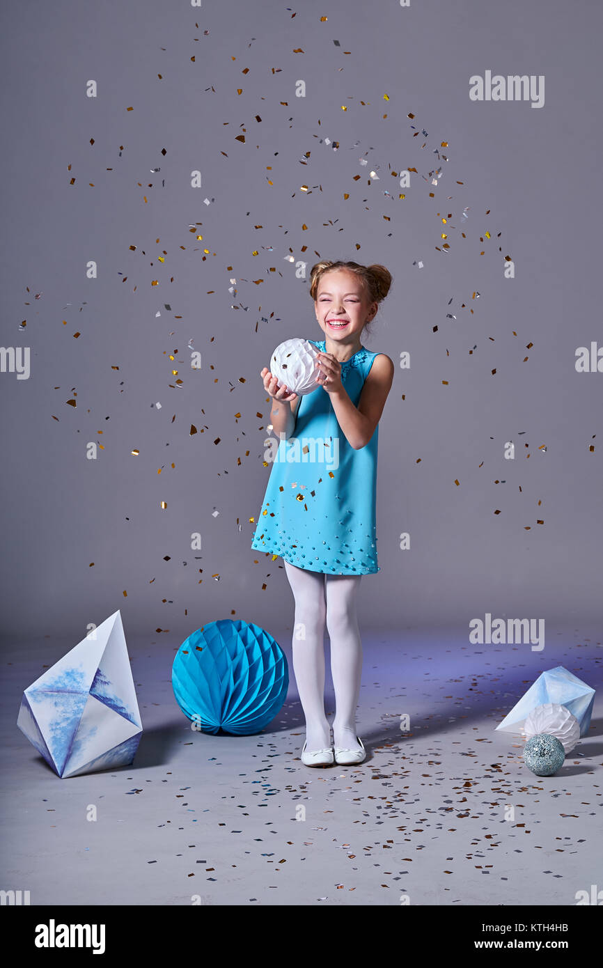 Cute baby girl in blue dress pretty model enjoying holiday and throwing confetti. Fashion kid christmas photos. Stock Photo