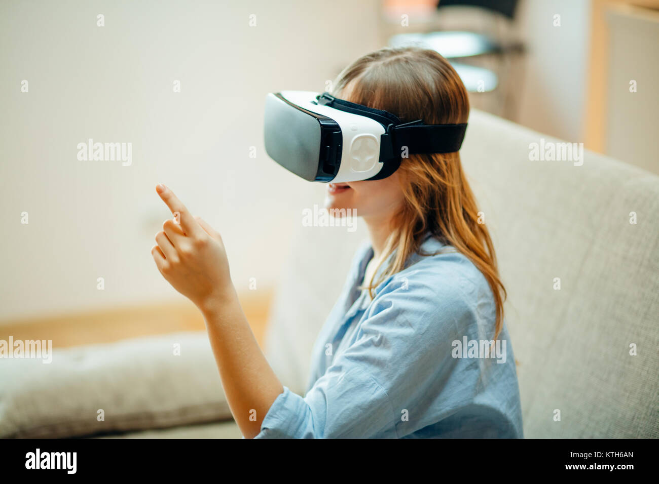 woman adjusting her VR headset and smiling while sitting on the carpet ...