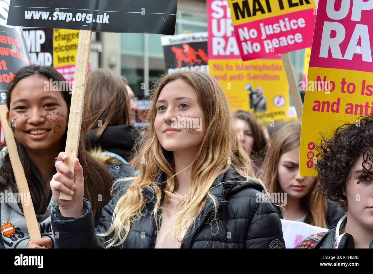 UN International Anti-Racism Day: Anti-racism protesters carry a message written on their faces 'Achievement has no colour' in London, UK. Stock Photo