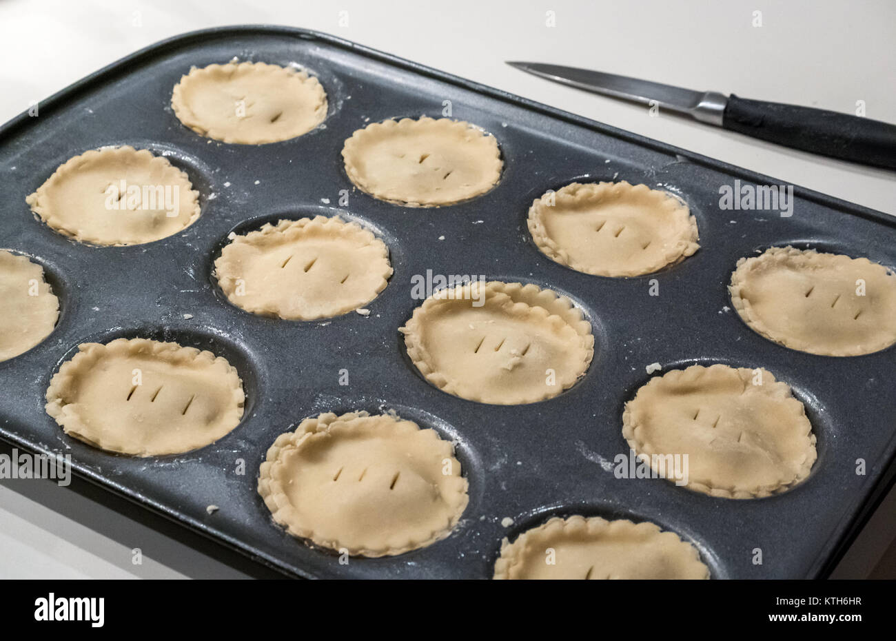 Close up of mince pies ready for baking in a pie tin on a white kitchen counter Stock Photo