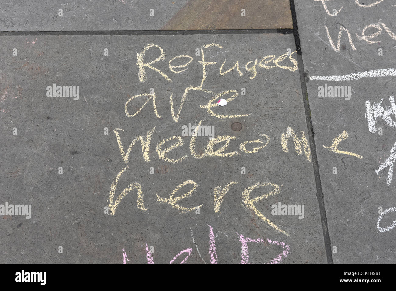 'Refugees are welcome here' message is written on the pavement by a child protester protesting against racism on UN Anti-Racism Day in London, UK. Stock Photo