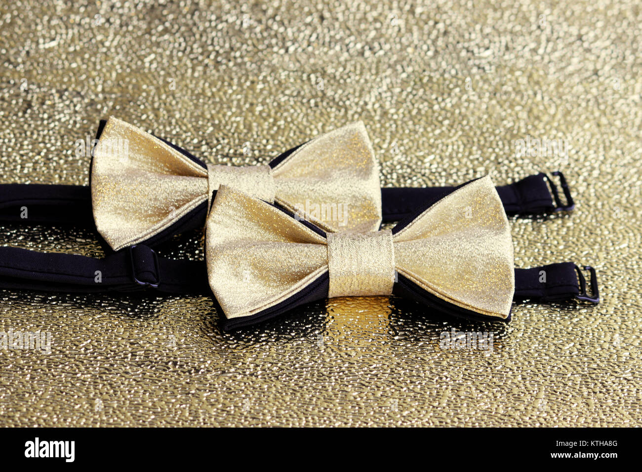 Two festive golden with a black bow tie on a gold background Stock