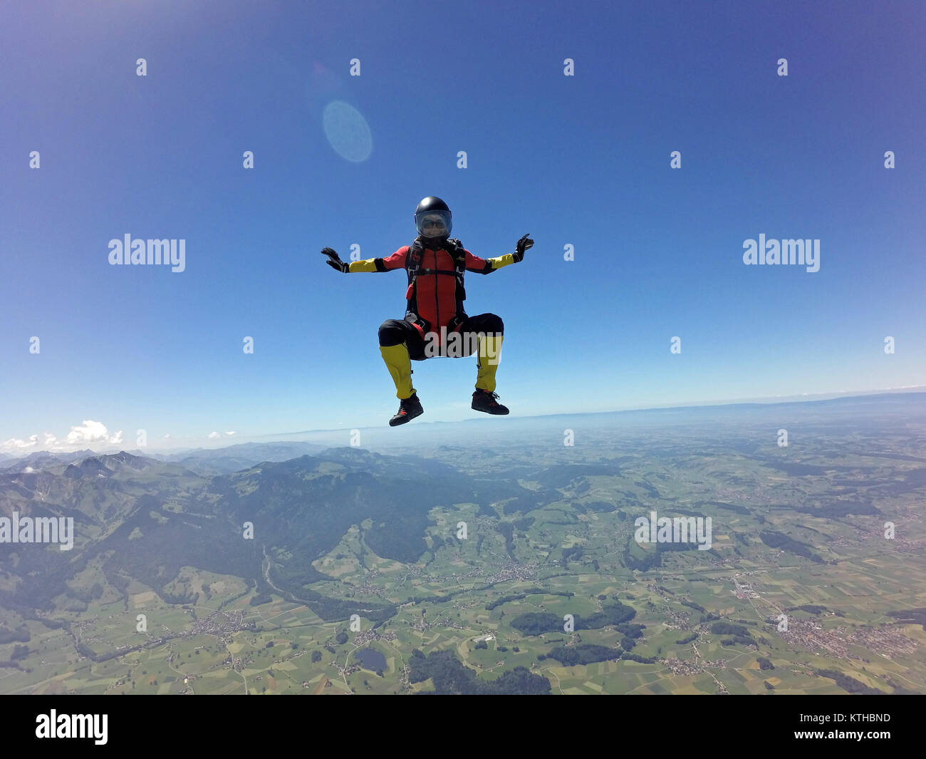 Look at this skydiving girl which is training the head up position over a beautiful landscape with high speed over 125 mph and a smile on her face. Stock Photo