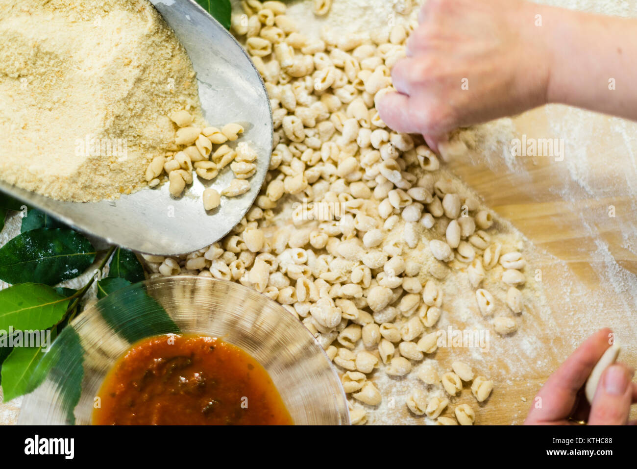 Woman making and preparing pisarei gnocchi typical pasta from Emilia Romagna, Piacenza, Italy at the restaurant kitchen preparation Stock Photo