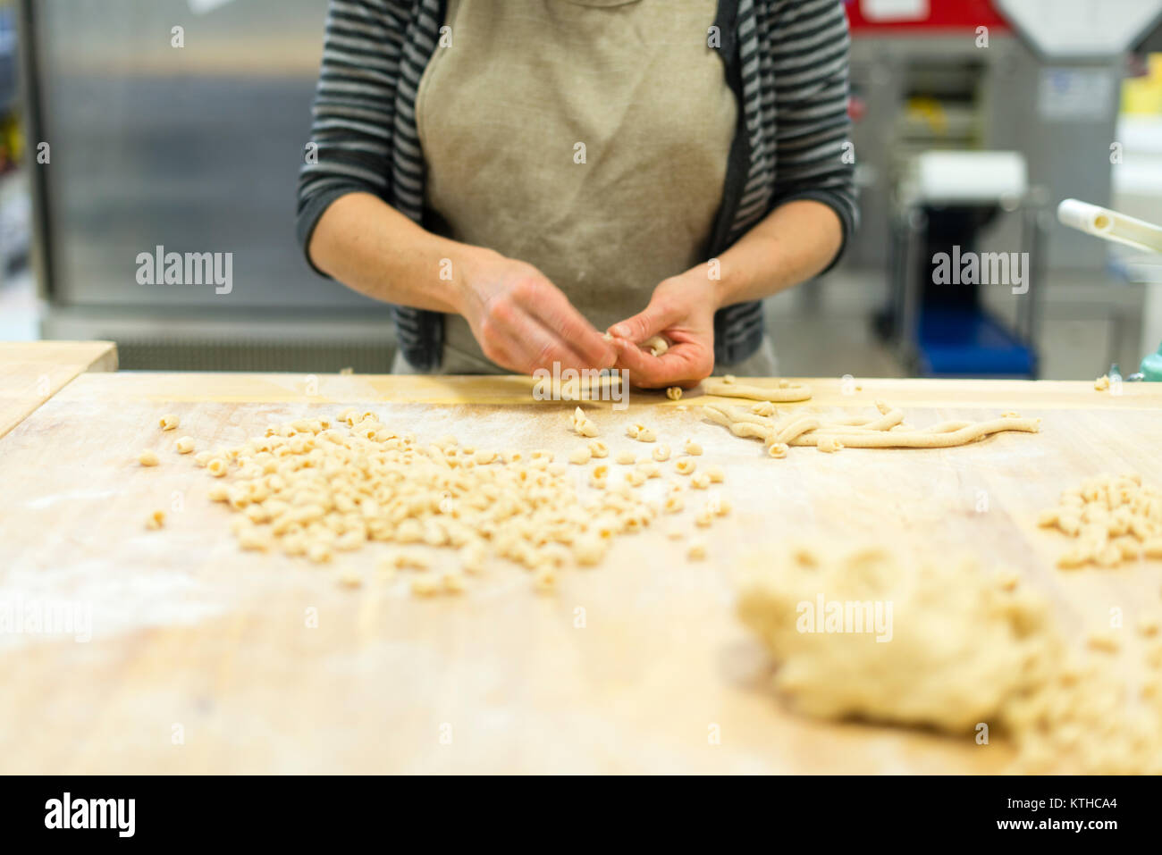 Woman making and preparing pisarei gnocchi typical pasta from Emilia Romagna, Piacenza, Italy at the restaurant kitchen preparation Stock Photo