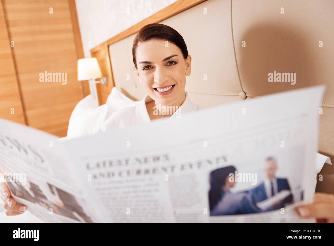 Jolly successful woman scrutinizing newspaper  Stock Photo
