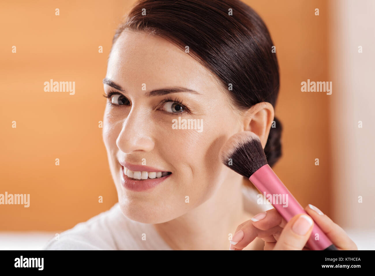 Appealing jolly woman using powder  Stock Photo