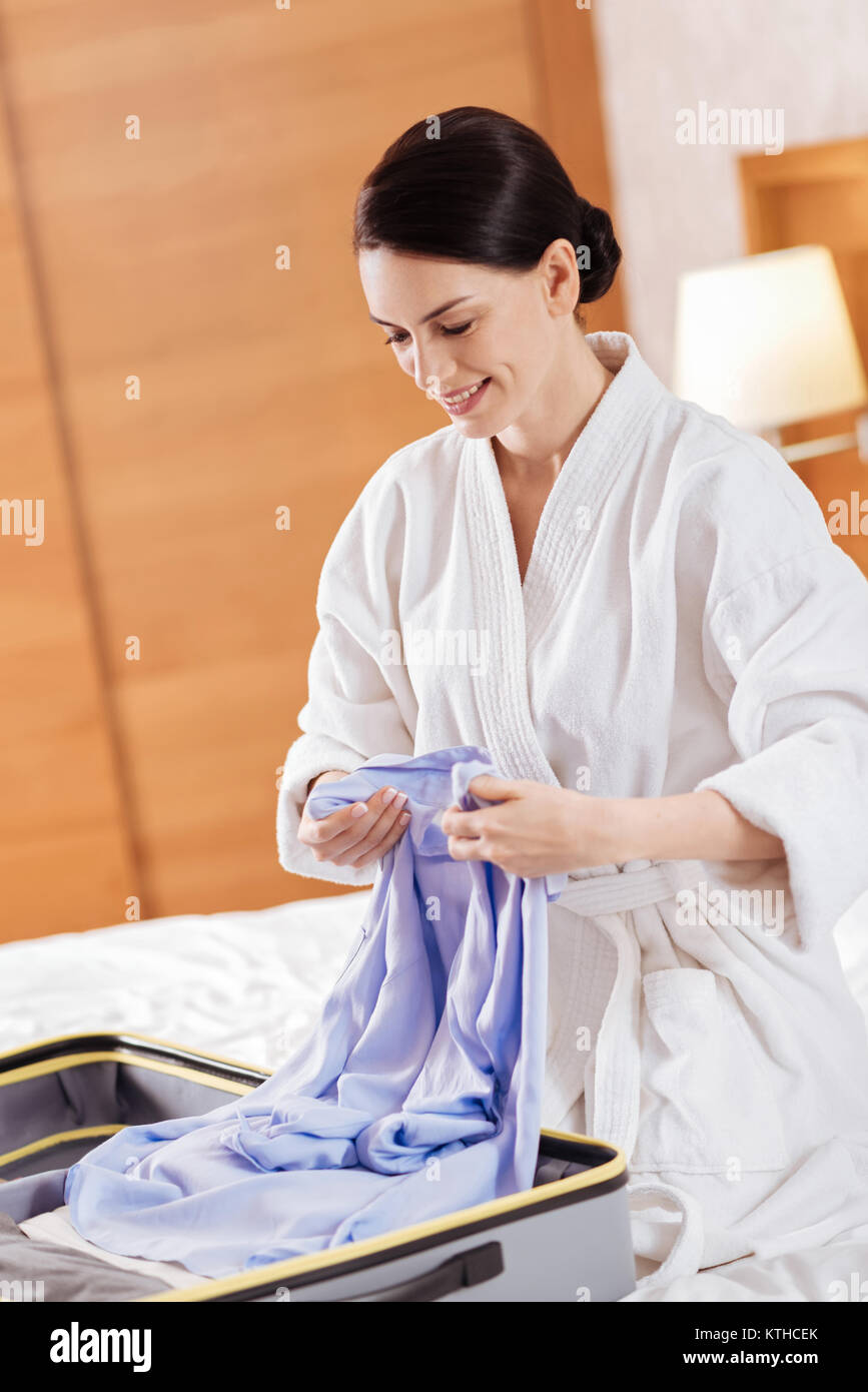 Pensive elegant woman placing shirt in the luggage Stock Photo