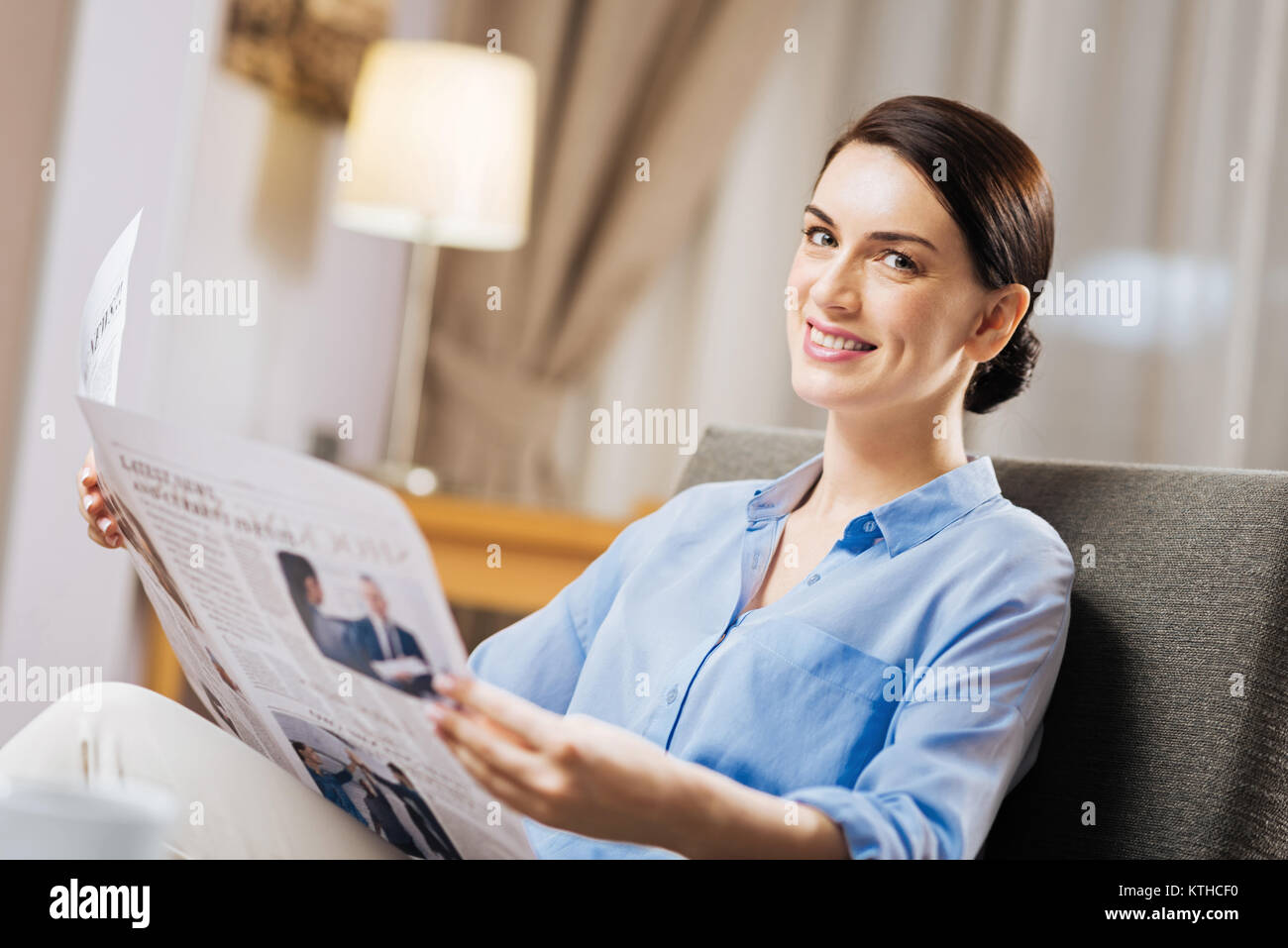 Brunette pleasant woman sitting with newspaper Stock Photo