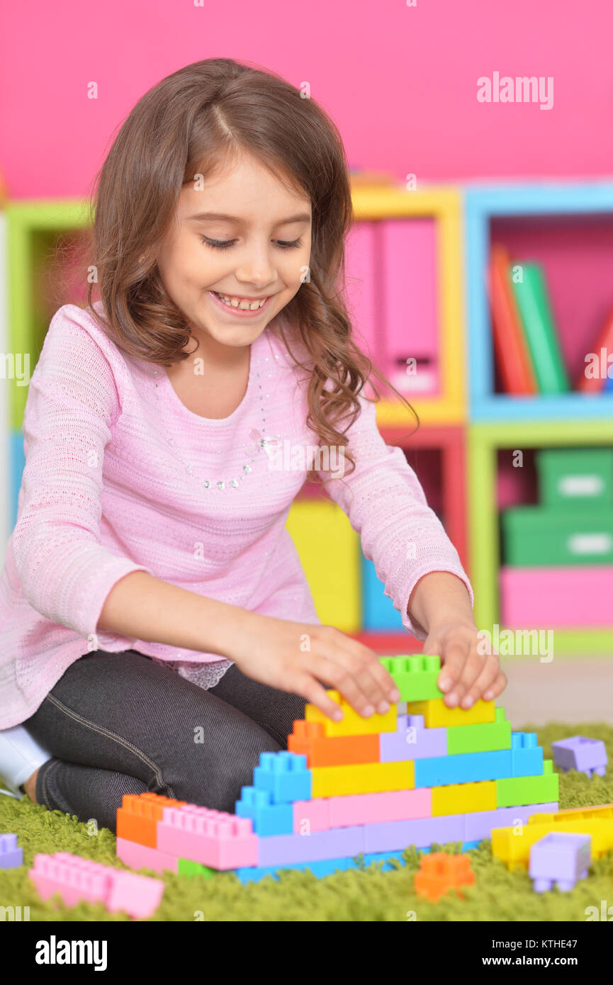 Cute girl playing with colorful plastic blocks on floor Stock Photo - Alamy