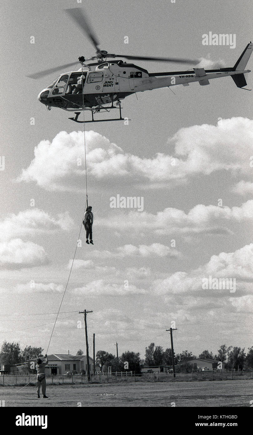 GOONDIWINDI, AUSTRALIA, CIRCA 1982: Unidentified crew members of the Queensland Government rescue helicopter lower a person to the ground from helicopter, circa 1982 in Goondiwindi, Australia Stock Photo
