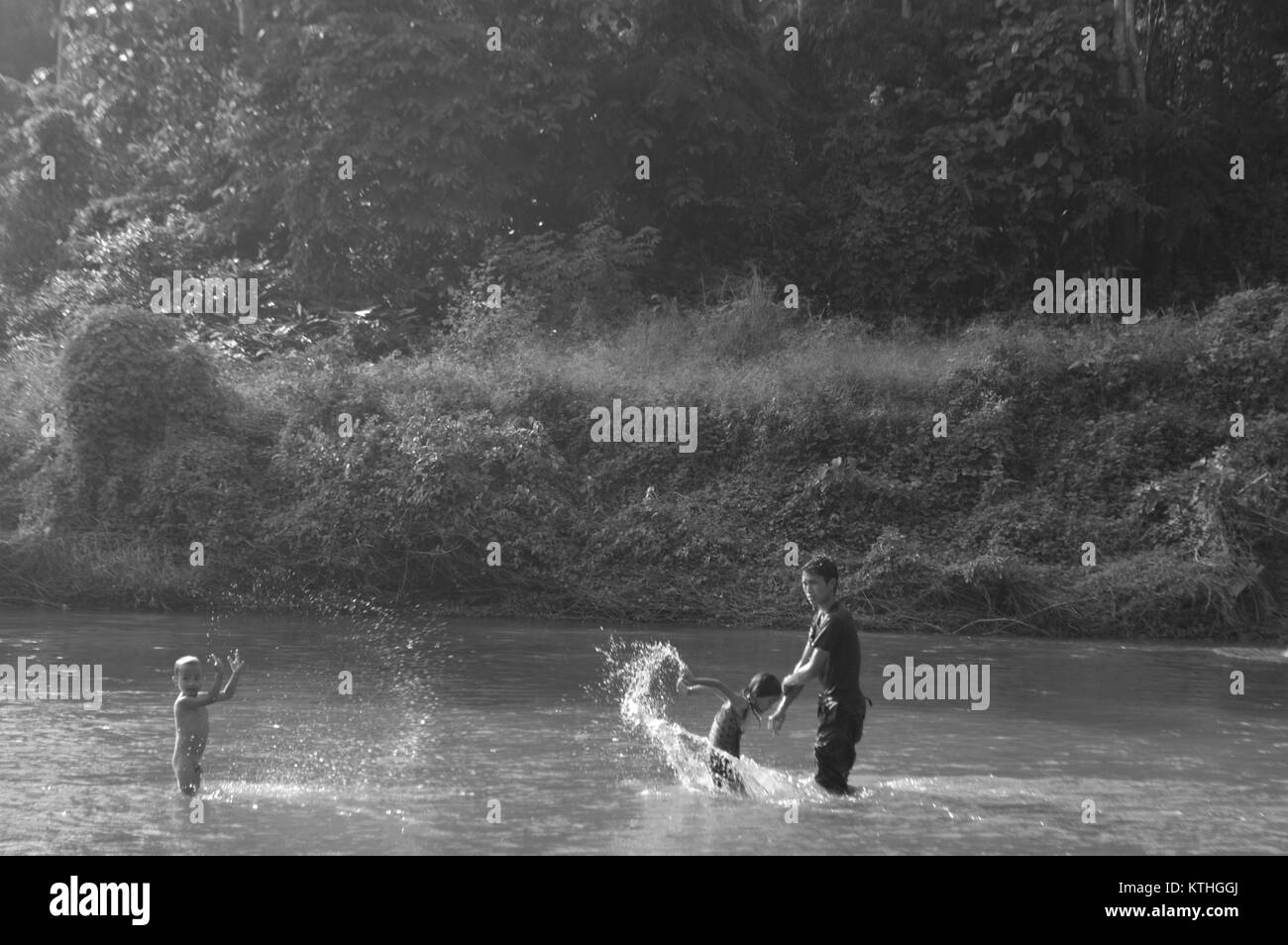 Kids playing and spashing water in river in Laos - Asia Stock Photo