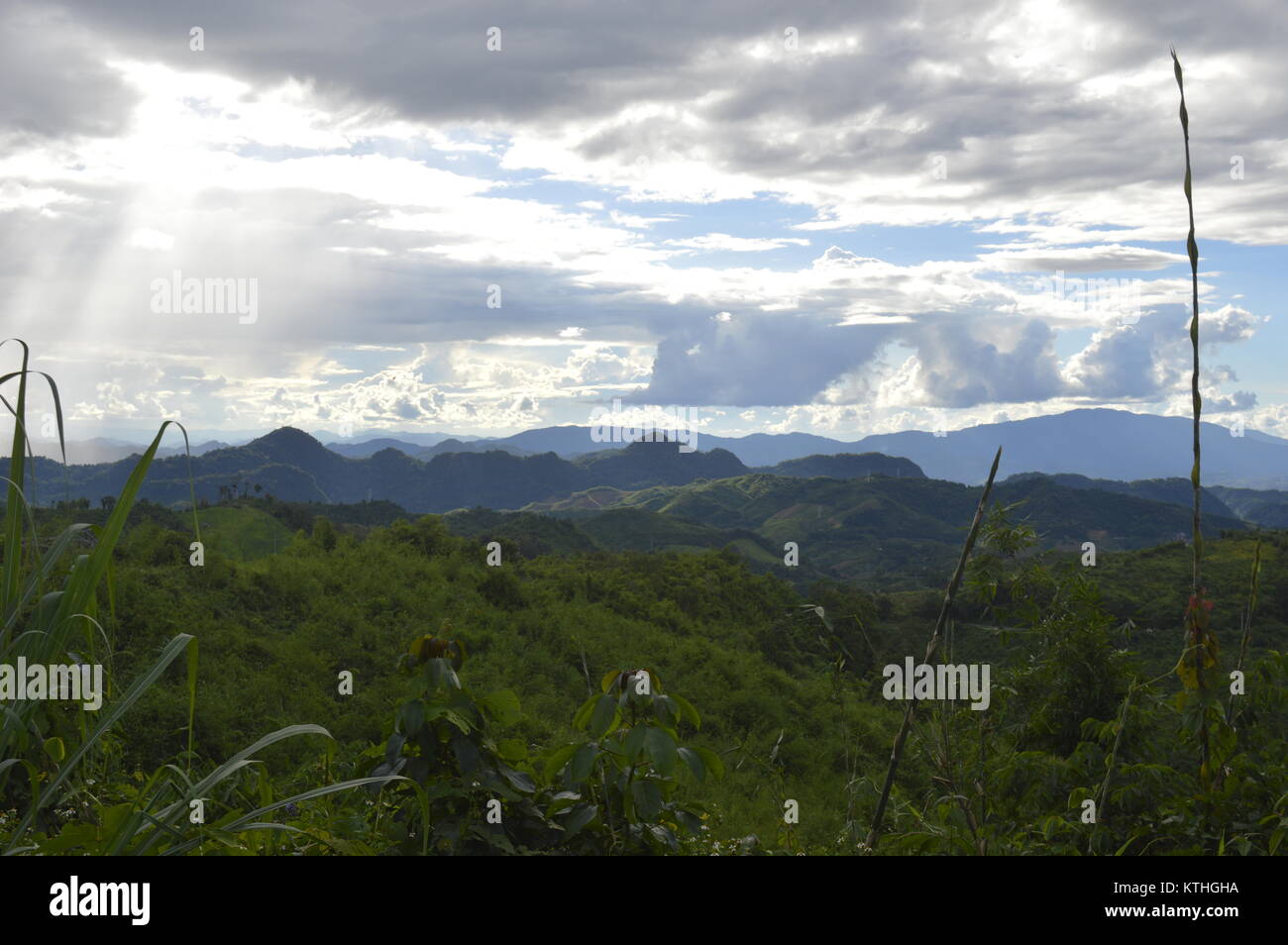 Beautiful mountain landscape with sun shining through clouds in sky in Laos - Asia Stock Photo
