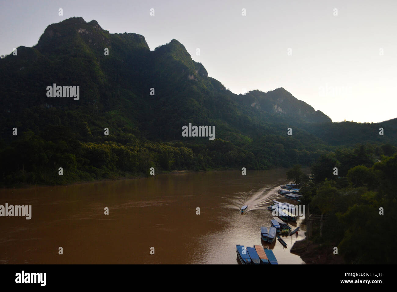 Asian boats on river surrounded by high mountains in Laos Stock Photo