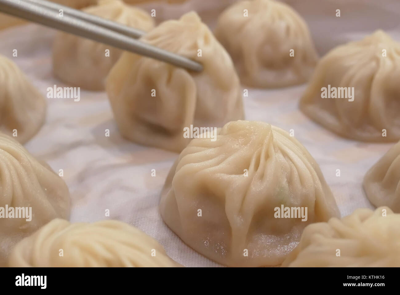 Motion of woman eating soup dumpling buns with chopsticks inside