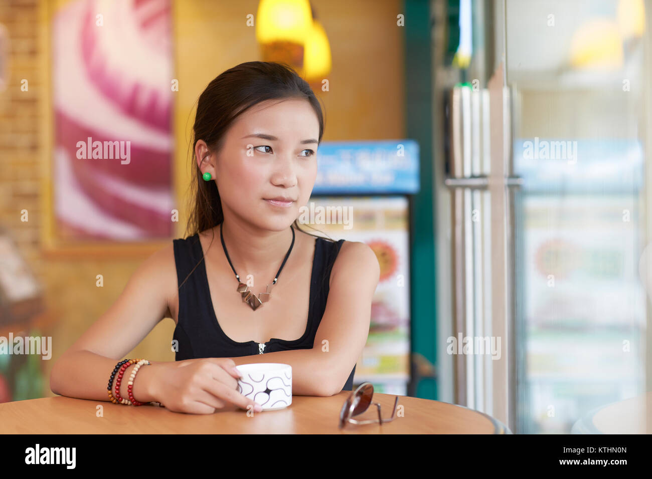 one young asian woman in cafe looking out of the window Stock Photo - Alamy
