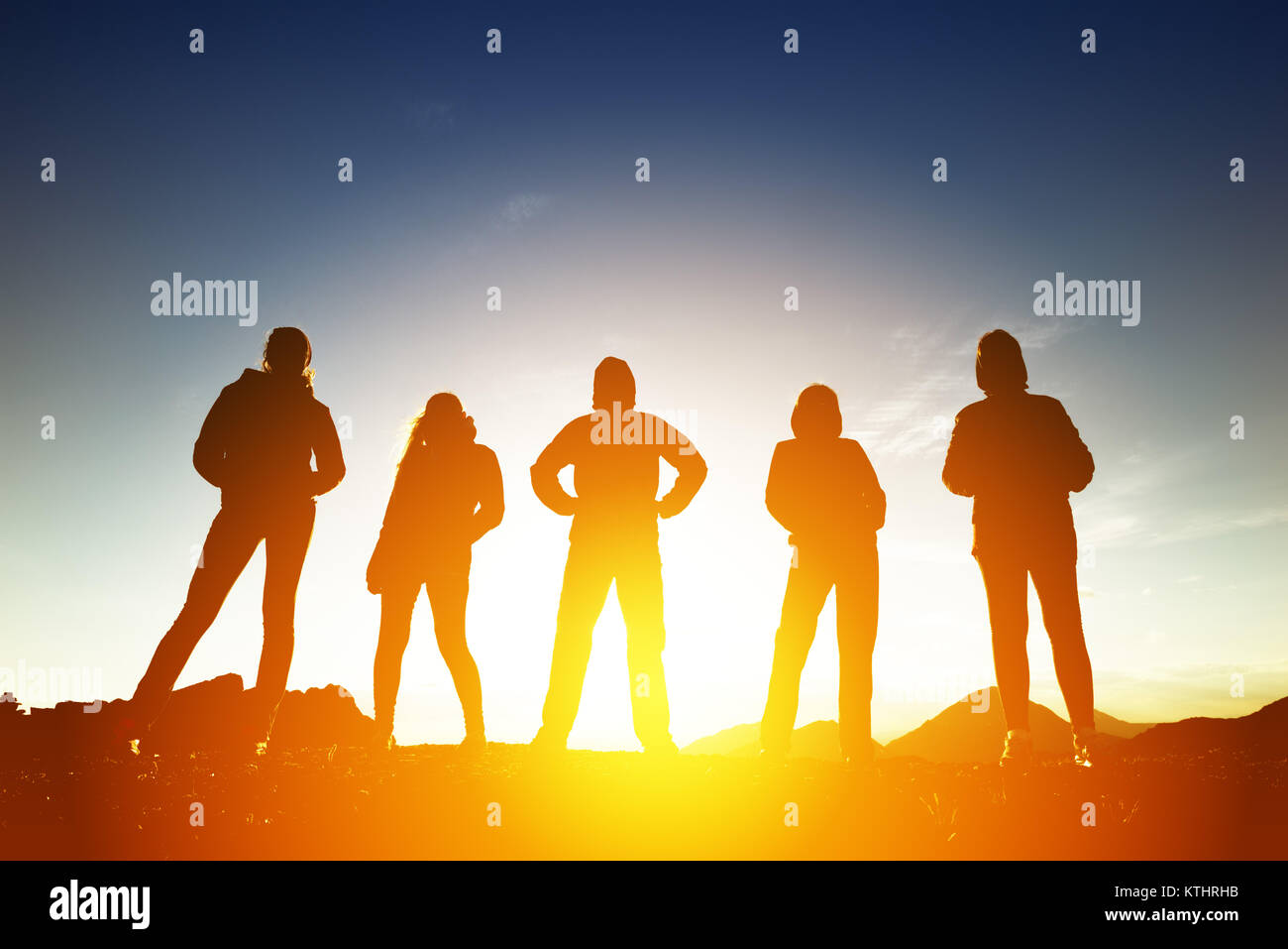Group of five peoples silhouettes in sunset light Stock Photo