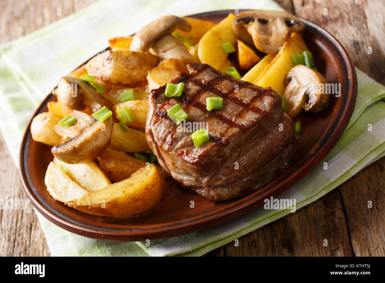 fillet mignon with fried potatoes and mushrooms close-up on a plate on a table. horizontal Stock Photo