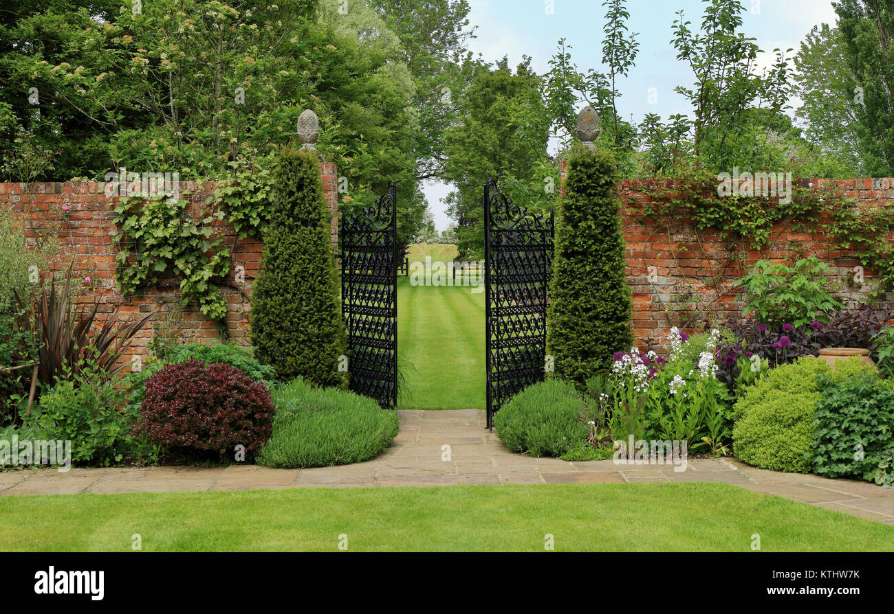 A Formal Landscape garden with wrought iron gates leading to a lawn Stock Photo