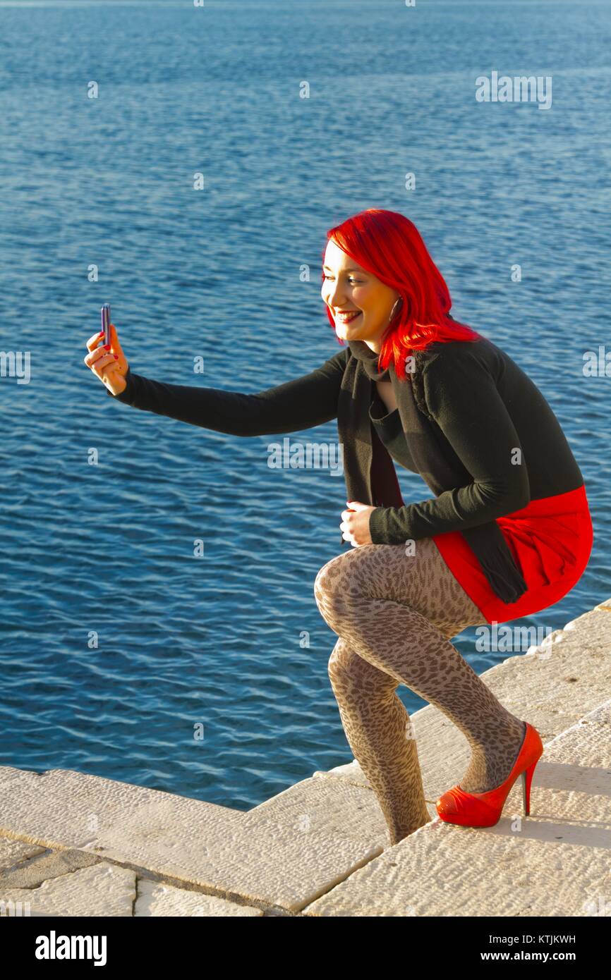 Feminine takes selfie photo with smarphone camera smiling smile happy happiness enthusiastic positive feeling model-released release alpfabet Stock Photo