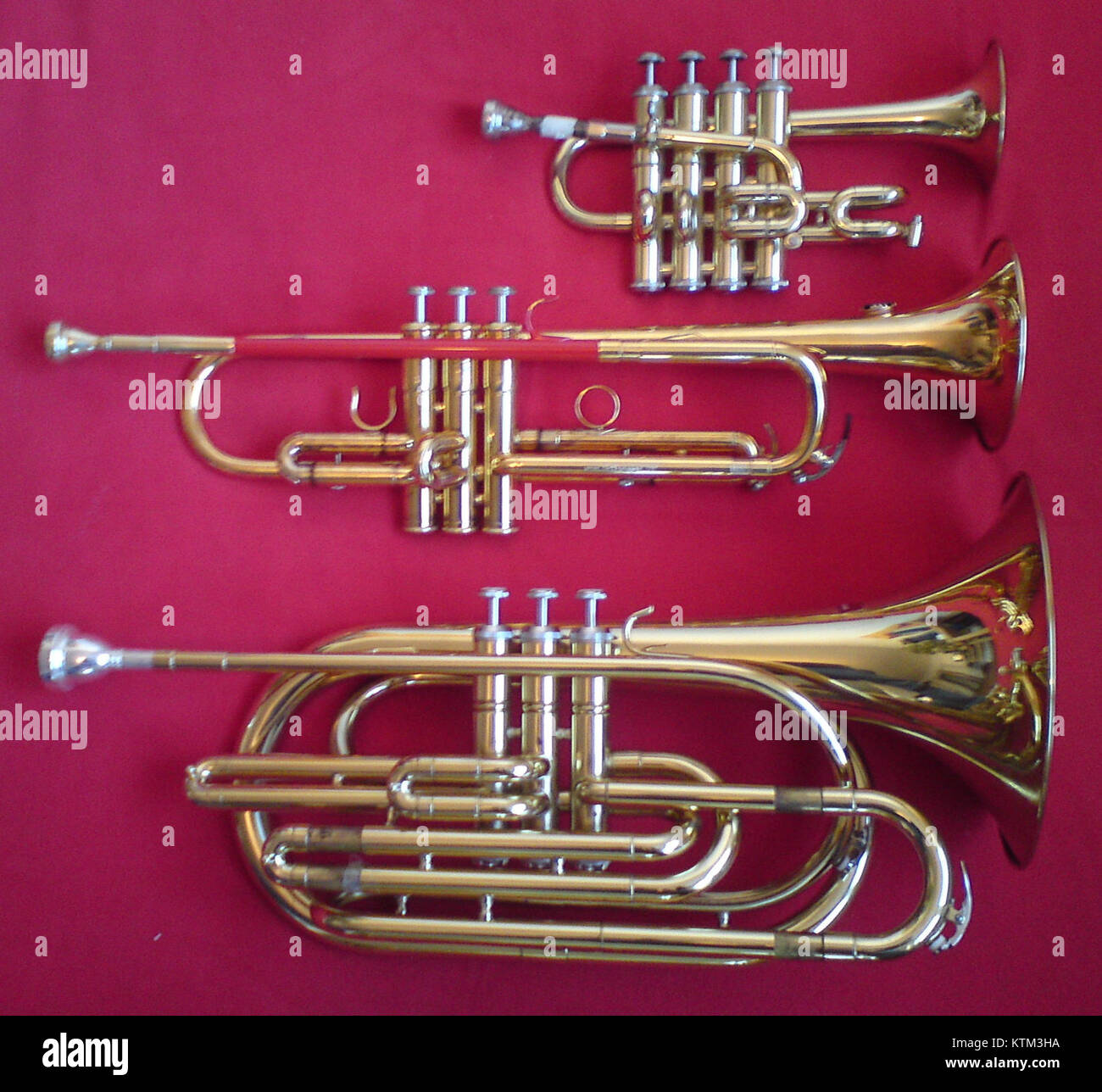 This image showcases three different types of trumpets: the bass trumpet, piccolo trumpet, and B flat trumpet. These brass instruments vary in size and pitch, and are used in different musical contexts to achieve distinct sound qualities. Stock Photo