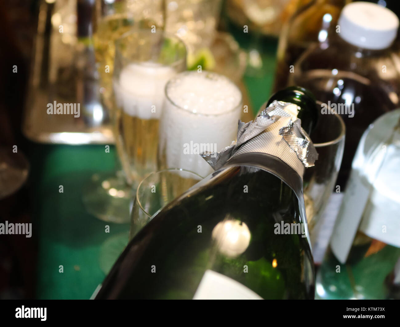 Bubbles coming off poured champagne in a foamy glass with surrounding bottle shapes and more champagne being poured Stock Photo