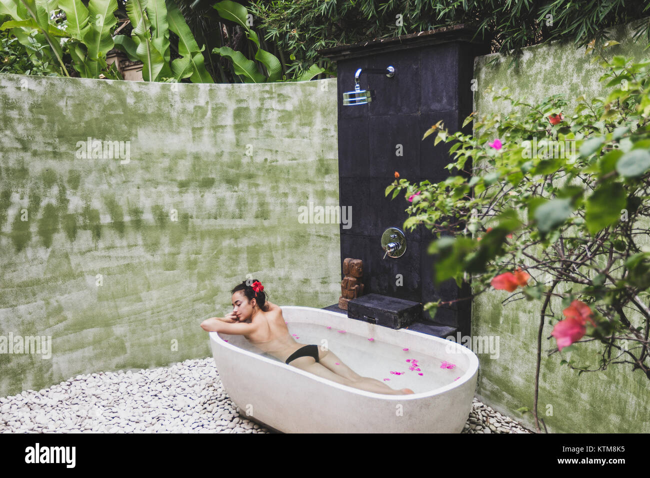Woman Relaxing In Round Outdoor Bath With Tropical Flowers