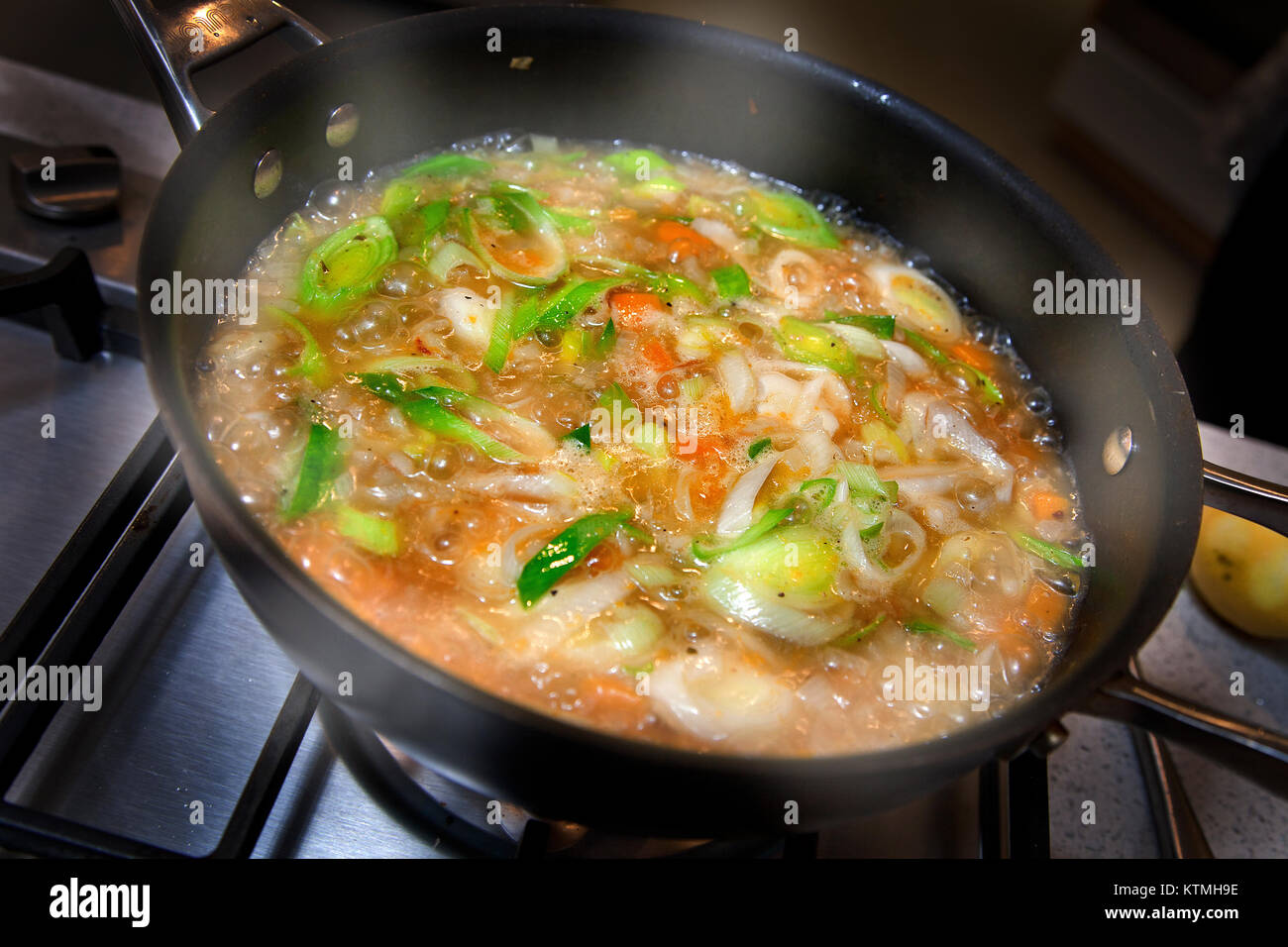 Vegetable soup simmering in pan on hob Stock Photo