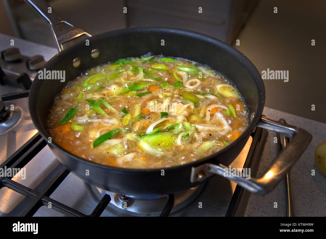 Vegetable soup simmering in pan on hob Stock Photo