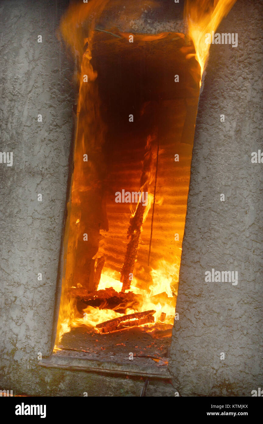 flames and smoke rise from door in burning farm building Stock Photo