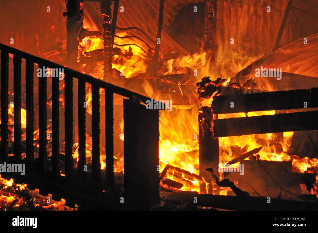 flames and smoke rise from burning house Stock Photo