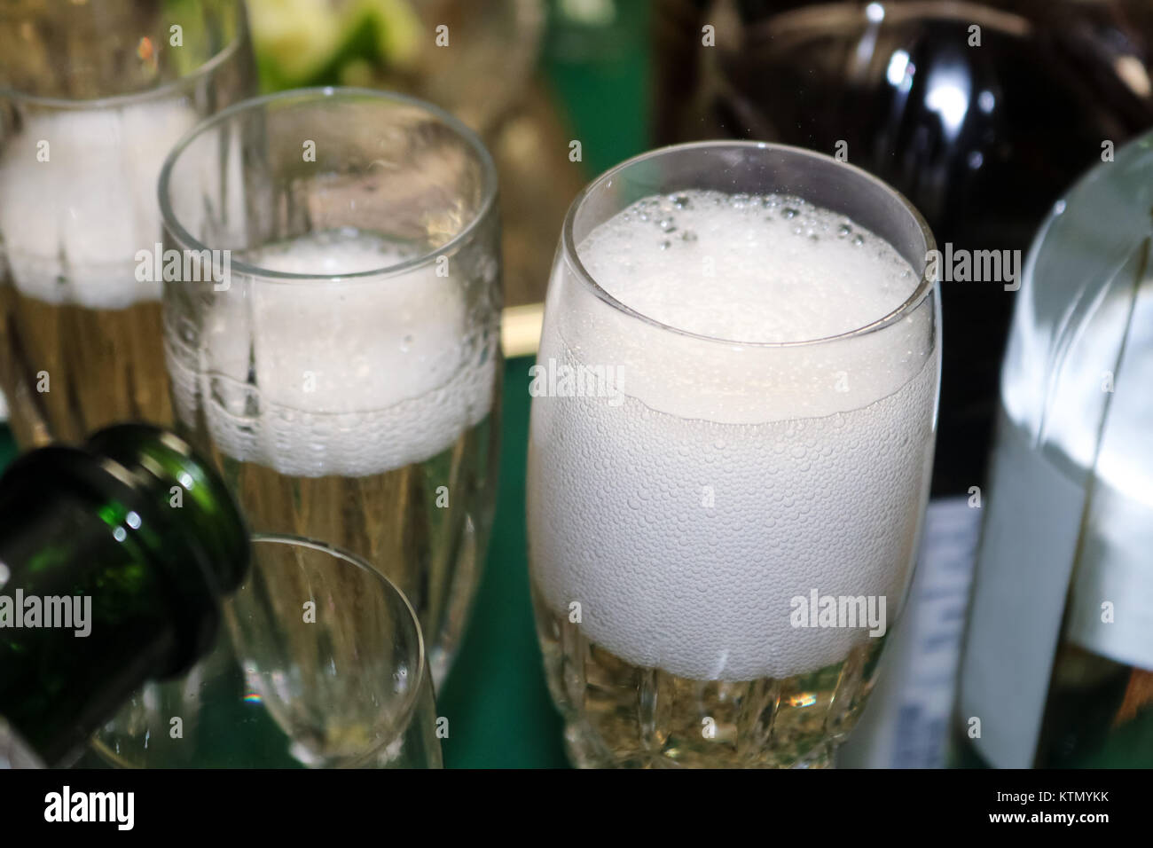 Bubbles coming off poured champagne in a foamy glass with surrounding bottle shapes and more champagne being poured Stock Photo