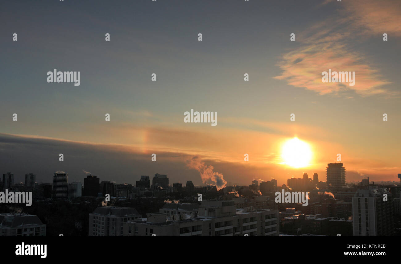 Toronto, Canada. 27th Dec, 2017. Polar stratospheric clouds, or nacreous clouds with setting sun and a short sun pillar and left sundog the rainbow like band on the left, over Toronto, in extreme cold weather on December 27, 2017 Credit: CharlineXia/Alamy Live News Stock Photo