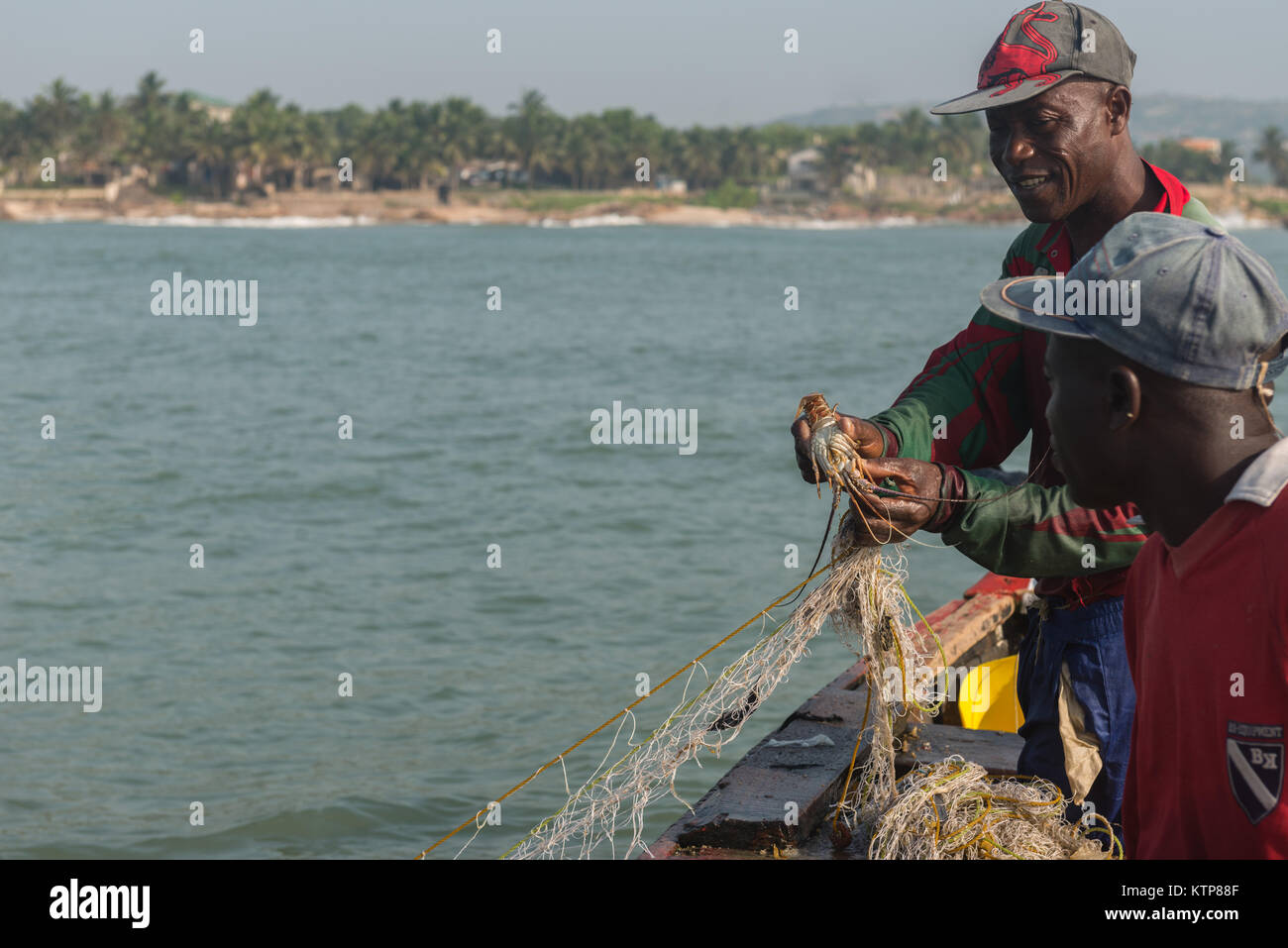 Fishermen in their open boat go fishing in the early morning. They paddle from net to net to fetch their catch, Kokrobite, Greater Accra Region, Ghana Stock Photo