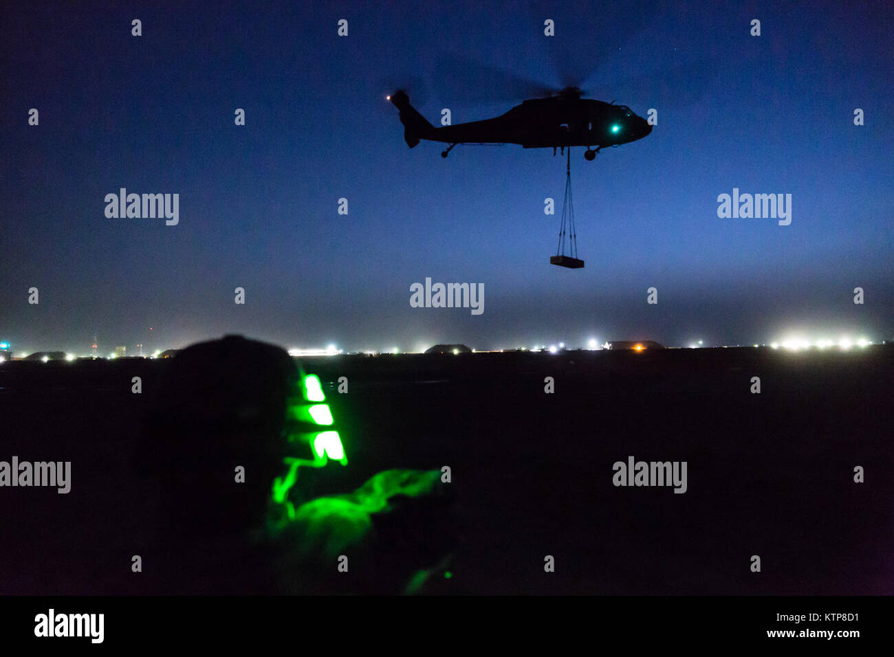 A UH-60 Black Hawk operated by Company A, 3rd Battalion, 142nd Assault Helicopter Battalion, flies off after picking up a 4,000 lb. weight during night sling load operations with the 642nd Aviation Support Battalion on June 5, 2014, in Camp Buehring, Kuwait.  The 642nd and 142nd, both under the 42nd Combat Aviation Brigade, New York Army National Guard, are deployed to Kuwait in support of Operation Enduring Freedom. (N.Y. Army National Guard photo by Sgt. Harley Jelis/Released) Stock Photo
