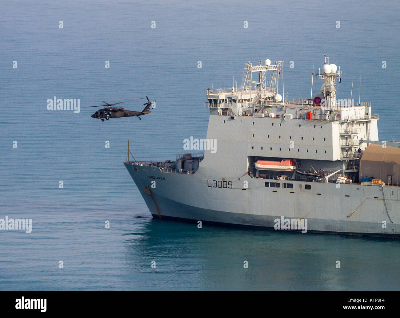 A UH-60 Medical Evacuation Black Hawk flown by pilots from 1st Battalion, 214th Air Ambulance, 42nd Combat Aviation Brigade (CAB), U.S. Army,flies past the RFA Cardigan Bay, Royal Fleet Auxiliary, U.K. Royal Navy, on June 8, 2014, somewhere in the Arabian Gulf.  The pilots trained on deck landings during Exercise Spartan Kopis, an exchange between the Cardigan Bay and both the Black Hawk and AH-64 Apache elements of the 42nd CAB, New York Army National Guard.    Spartan Kopis was the first time American Apaches worked with a Royal Navy ship to function as its eyes and ears during an escalation Stock Photo
